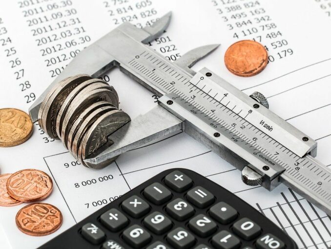 Taschenrechner, Münzen und Kalkulation: Einsparungen, um Schulden loszuwerden