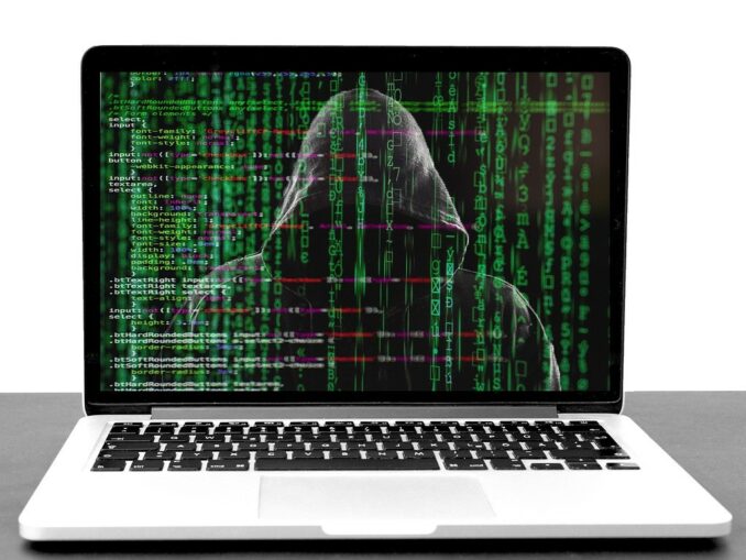 Laptop mit einem Hacker und Codes auf dem Bildschirm: Sparkasse Phishing Mails haben Konjunktur!