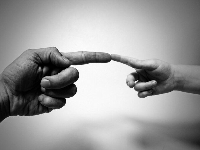 Finger eines Erwachsenen und Finger eines Kindes, die sich berühren: Sparen für den Nachwuchs kann sehr sinnvoll für Ihr Kind / Ihre Kinder sein!