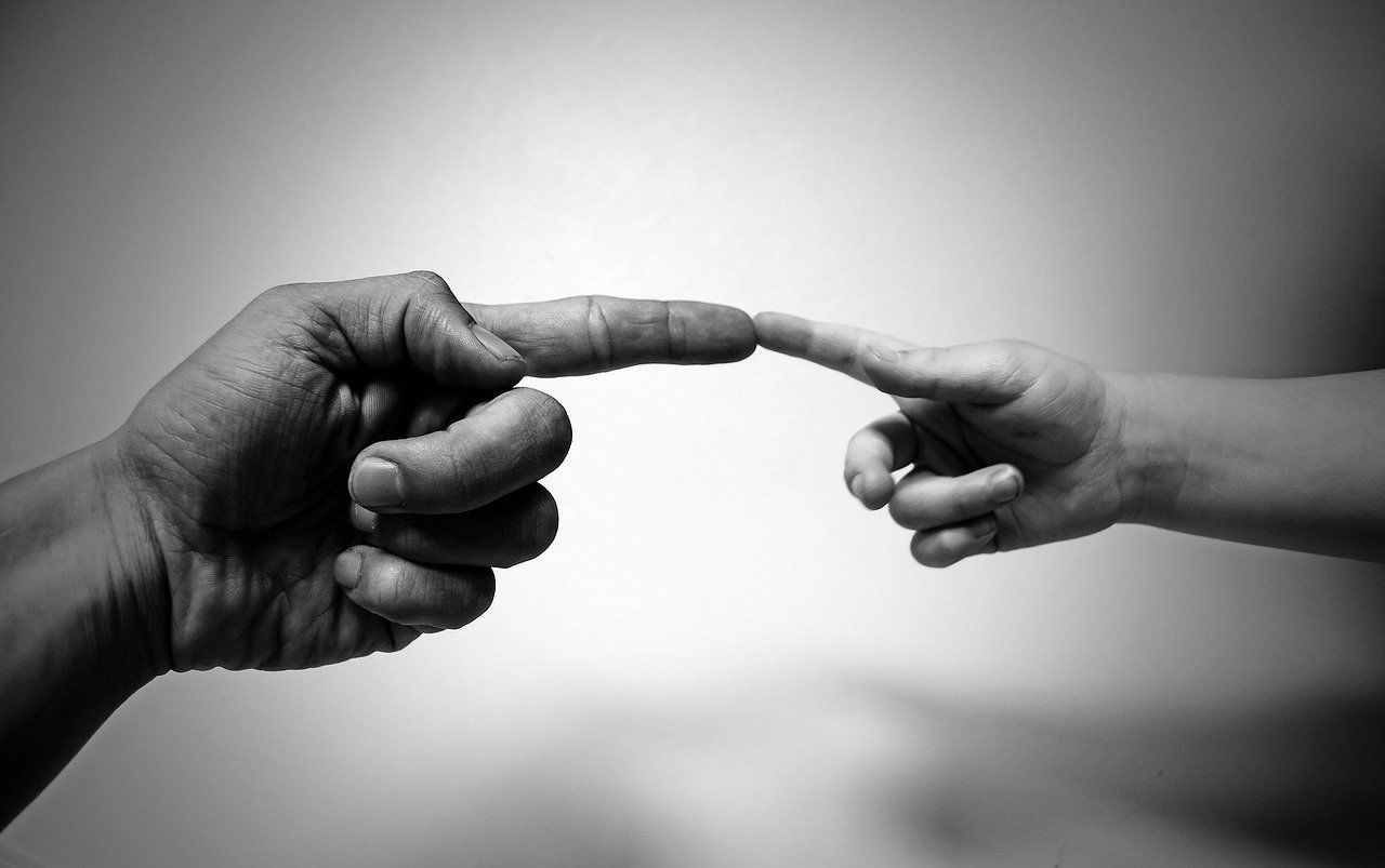 Finger eines Erwachsenen und Finger eines Kindes, die sich berühren: Sparen für den Nachwuchs kann sehr sinnvoll für Ihr Kind / Ihre Kinder sein!